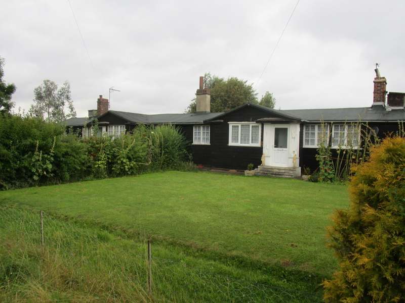 Single storey home behind a wide lawn with a hedge and fence line