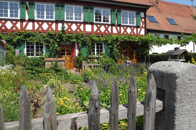 Timber picket fence in front of a garden and house